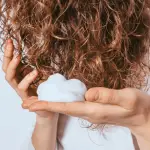 Womans-hands-apply-styling-mousse-to-her-curly-hair